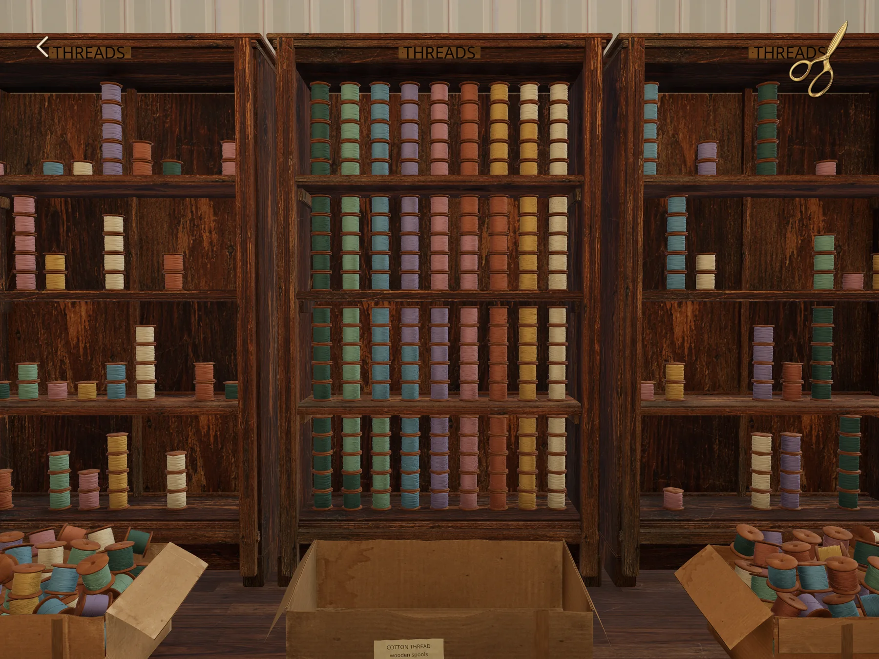 Three wooden thread cabinets. The middle one is filled in neat columns of spools sorted by colour, from dark green through blue, lavender, pink, rust, mustard and cream; open cartons of loose spools sit on the floor.
